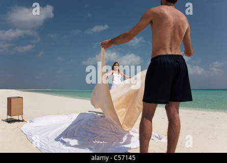 Couple making bed on beach Stock Photo
