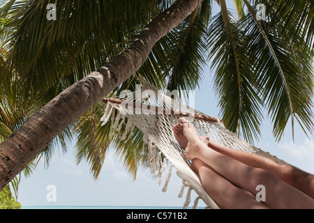 Couple laying in hammock under palm tree Stock Photo