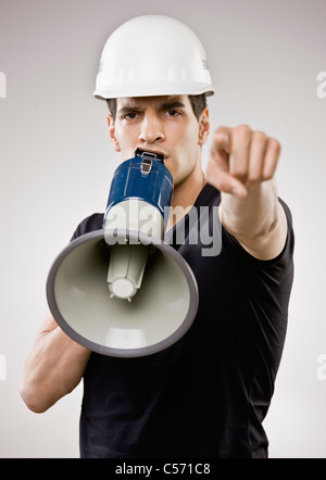 Man in hard hat using megaphone Stock Photo