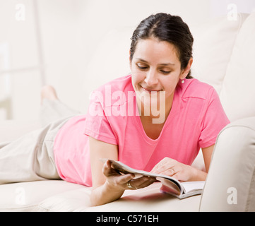 Woman reading magazine on couch Stock Photo