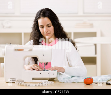 Woman using sewing machine at home Stock Photo