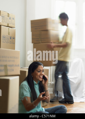 Woman on phone and unpacking boxes Stock Photo