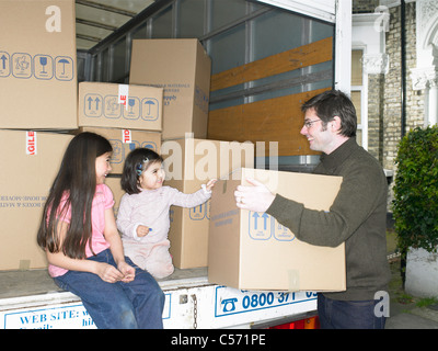 Family unpacking boxes from moving van Stock Photo