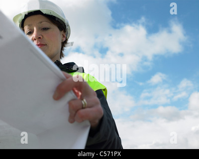 Worker examining blueprints on site Stock Photo