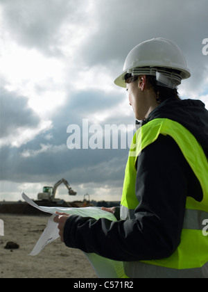 Worker examining blueprints on site Stock Photo