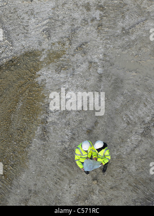 Workers discussing blueprints on site Stock Photo