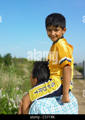 Son sitting on father’s shoulders Stock Photo