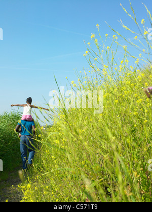 Daughter on father’s shoulders in field Stock Photo