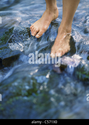 Feet walking on river rocks Stock Photo