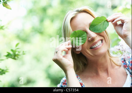 Smiling woman playing with leaves Stock Photo