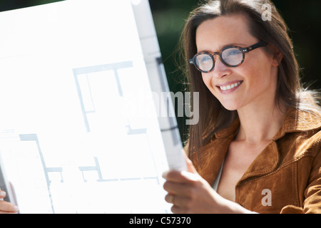 Woman reading blueprints outdoors Stock Photo
