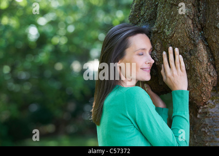 Smiling woman hugging tree Stock Photo