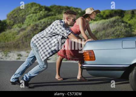 Couple pushing broken down car Stock Photo