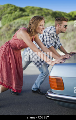 Couple pushing broken down car Stock Photo