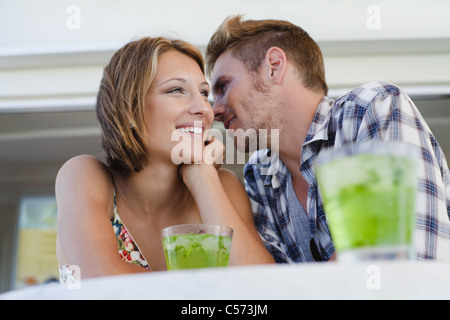 Couple whispering together at cafe Stock Photo