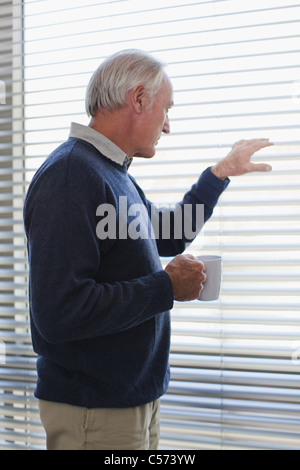 Businessman peering out office window Stock Photo