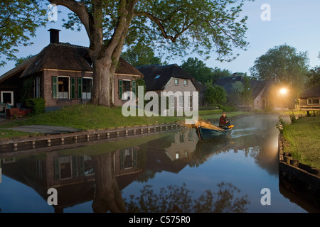 The Netherlands, Dwarsgracht, near Giethoorn. Village with almost only waterways. Houses at dawn. Farmer transporting reed for roofconstruction. Stock Photo