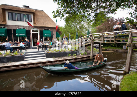 The Netherlands, Giethoorn, Village with almost only waterways. Italian restaurant and outdoor cafe. Boat pasing. Stock Photo