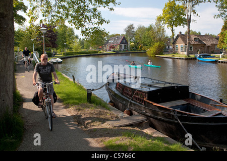 The Netherlands, Giethoorn, Village with almost only waterways. Tourists enjoying kayak ride and cyclists. Stock Photo