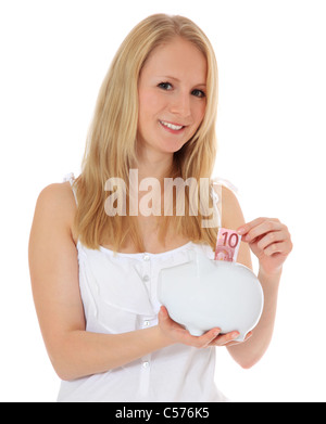 Attractive young woman puts money in her piggy bank. All on white backgorund Stock Photo