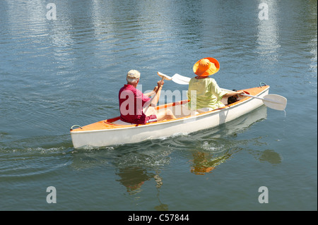 Older couple rowing canoe on lake Stock Photo