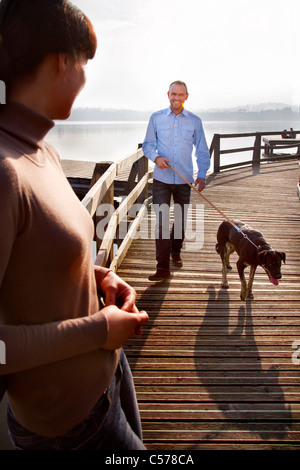 Couple walking dog on pier Stock Photo