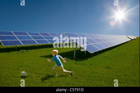 Boy playing in field by solar panels Stock Photo