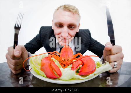 Businessman eating plate of lobster Stock Photo