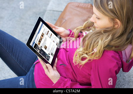 Close up picture of a young woman reading 'Dolce and Gabanna' Facebook Fan's Page on an iPad 2 Stock Photo