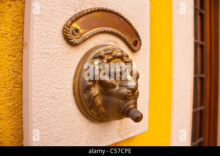 Door bell with lion head on white wall Stock Photo