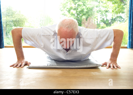 Older man doing pushups indoors Stock Photo