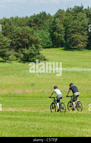 Sport mountain biking happy couple riding downhill in sunny countryside Stock Photo