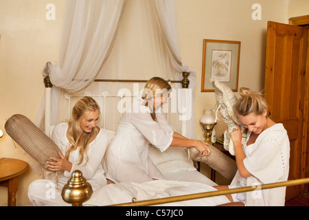 Mother and daughters having pillow fight Stock Photo
