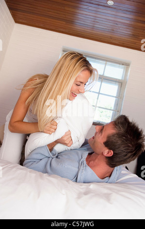 Couple having pillow fight in bed Stock Photo