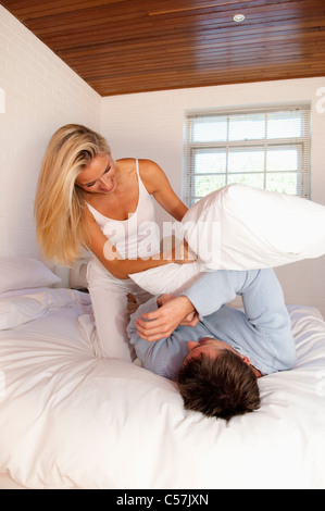 Couple having pillow fight in bed Stock Photo