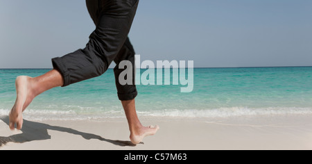 Businessman running on tropical beach Stock Photo