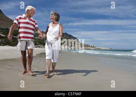 Older couple walking together on beach Stock Photo