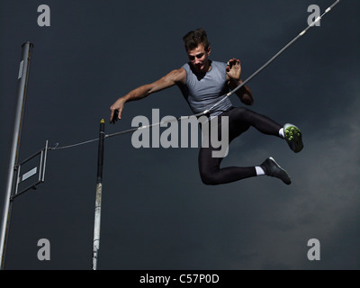 Man jumping midair in pole vault Stock Photo