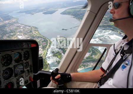 pilot flying helicopter flight over niagara falls ontario canada focus on falls Stock Photo