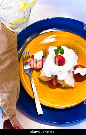 Strawberry shortcake with fresh berries and whipped cream. Ice water with lemons. Stock Photo