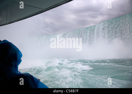 tourist in blue plastic waterproof poncho under the horsehoe falls on the maid of the mist niagara falls ontario canada Stock Photo