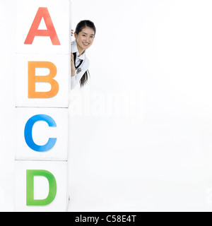 Portrait of teenage girl hiding behind block Stock Photo