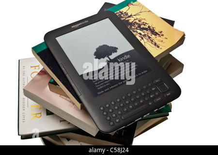 An Amazon Kindle e-reader on top of a large stack of assorted books and novels against a plain white background Stock Photo