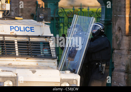 Police officer aims a Heckler and Koch L104A1 37mm single-shot AEP launcher at rioters Stock Photo