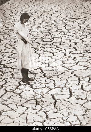 A woman stands looking at the parched ground at The Tring Reservoir, Tring, Hertfordshire, England during the drought of 1934. Stock Photo