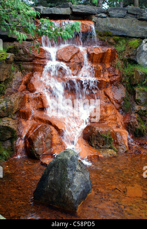 The Red Rocks waterfall cascading over a rugged landscape of rocks in ...