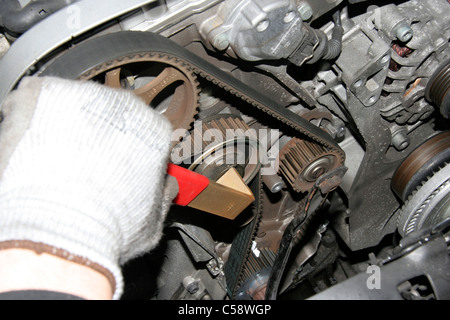 A Motor Technician in the Process of changing a VW Timing Belt using a Two Prong face spanner Stock Photo