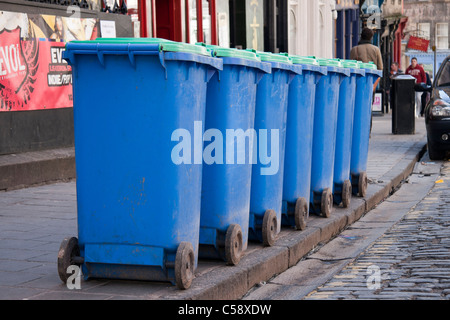 A neat row of blue wheelie bins arranged on the kerb-side of a cobbled street in Edinburgh Stock Photo