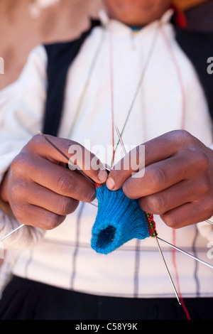 A male weaver of Taquile, a traditional island on Lake Titicaca knitting wearing a hat or chullo. They are woven on the island. Stock Photo