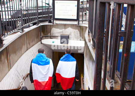 French rugby fans wrapped in national flags enter the Tube in London ahead of a game involving their team Stock Photo